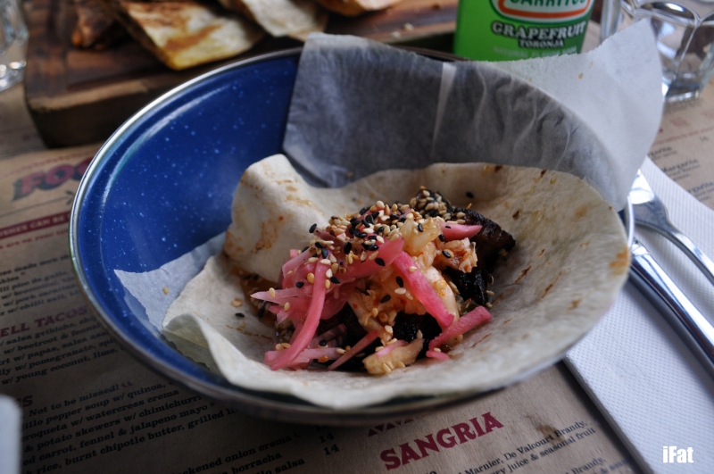 Taco with braised pork belly, pomegranate, spiced cabbage and sesame